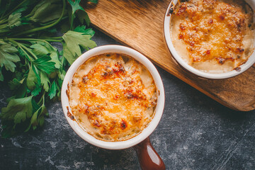 Julienne in portions, Mushrooms with cream and cheese casserole, Restaurant food on a dark background, Top view