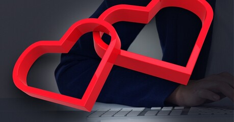 Two red hearts against against mid section of businessman using laptop