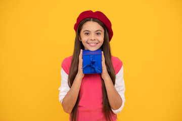 happy teen girl in french beret hold present or gift box on yellow background, present