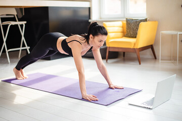 Plakat Woman watching tutorial on laptop while training at home