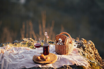 A bottle of wine with glass for wine, croissants and a basket with baguette lie on a plaid on the...
