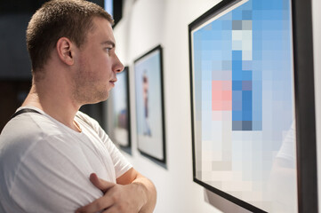 Fototapeta premium Young man in modern art exhibition gallery hall contemplating artwork. Abstract painting