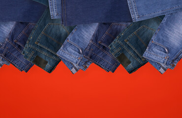 Jeans folded on red background, Top view with copy work space.