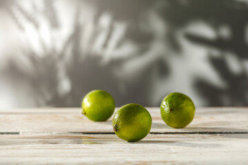 Mint lime on a wooden white table on a summer day and shadows of leaves on the wall 