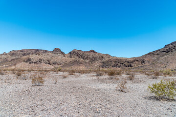 Barren desert valley with barren mountains under a clear blue sky