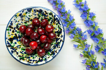 fresh ripe cherries in a bowl on white wooden background