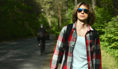 Male tourist with backpack walking near the road.