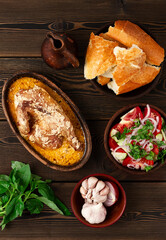Traditional Georgian dish, Chkmeruli, chicken in creamy garlic sauce, in a clay pan, ketsi, on a wooden table, no people,
