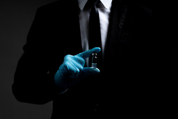 Businessman with black business suit wearing medical protection gloves holding medical  coronavirus vaccine for prevention covid-19 or coronavirus with black background and copy space. Vaccine concept