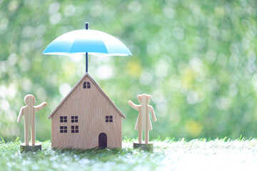Protection,Love couple and model house under the umbrella on natural green background, Safe investment and save money for prepare in future concept