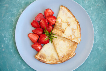 Pancakes, thin pancakes with fresh strawberries. On the background. View from above. Copy space.