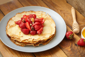Pancakes, thin pancakes with fresh strawberries. On a wooden background. Copy space.