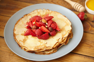 Pancakes, thin pancakes with fresh strawberries. On a wooden background. Copy space.