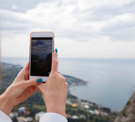 close-up photography. female hands taking pictures of the sea on the phone