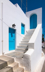 Outdoor staircase of white washed house with blue doors and closed shutters on a sunny day in Kythira, Greece.