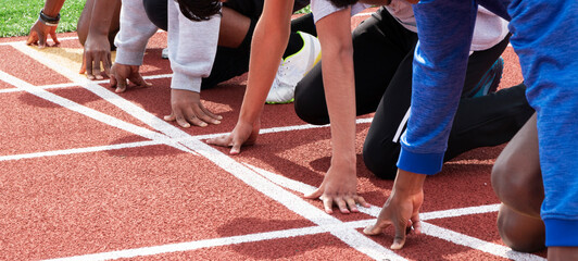 Hands and arms of five sprinter runners ready to start a race at practice