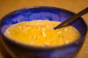 Kheer (Indian rice pudding), garnished with almonds, in a blue bowl with a silver spoon