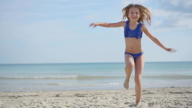 Cheerful carefree girl in a bathing suit dancing on the sandy seashore. Rest during the holidays. Great mood.