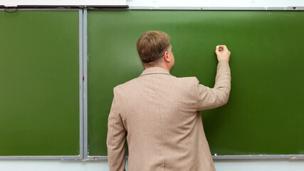 Math teacher writes chalk on blackboard copy space.