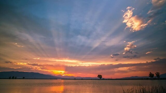 Sun rays reaching into the sky during sunset timelapse over Utah Lake.