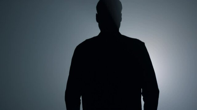 Silhouette man going away in dark background. Back view guy walking in darkness.