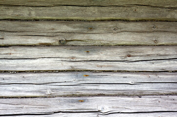 A wall of an old village house made of wooden logs. Gray natural background