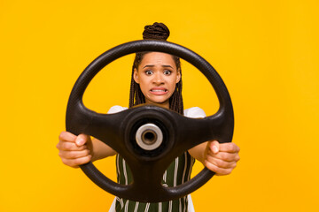 Photo of unhappy scared young afro american woman hold steering wheel isolated on yellow color...