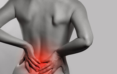 Naklejka premium Woman having backache, pain back isolated on gray background. Scoliosis. Spinal cord problems on womans back. monochrome photo with red as a symbol for the hardening