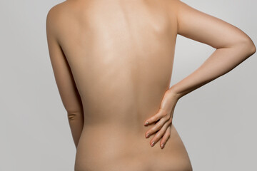 Fototapeta na wymiar Woman having backache, pain back isolated on gray background. Scoliosis. Spinal cord problems on womans back. Beautiful naked woman touching her back.