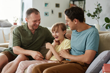 Gay family having fun together with adopted daughter at home