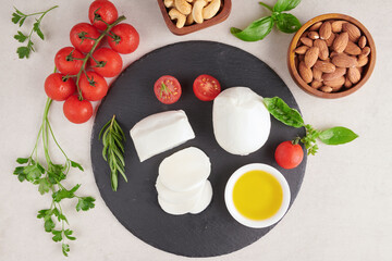 Fototapeta na wymiar Fresh mozzarella cheese, Soft italian cheeses, tomato and basil, olives oil and rosemary on wooden serving board over light wooden background. Healthy food. Top view. Flat lay.