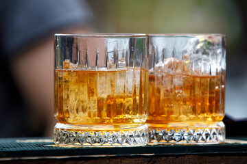 Two glasses of whiskey with ice.