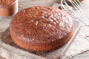 Fototapeta na wymiar Homemade chocolate sponge cake or chiffon cake so soft and delicious with ingredients: eggs, flour, cocoa, milk on wood table. Homemade bakery concept for background and wallpaper