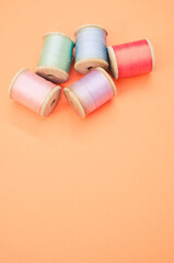 Colorful sewing threads isolated on a pastel orange background with free space for text