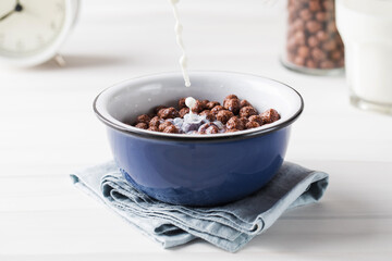 Milk is poured into a plate with round cocoa flakes. Dry breakfast.