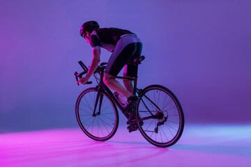 Naklejka na ściany i meble Cyclist riding a bicycle isolated against neon background