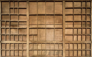 Background from an old wooden type case with many small empty compartments, which is very weathered and shows traces of use