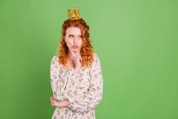 Photo of minded dreamy young woman look empty space wear crown royal isolated on green color...