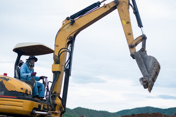 mini excavator digging soil with mountain background