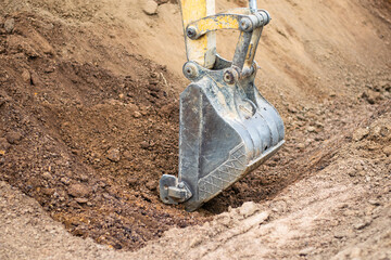 A mini excavator is digging the soil in the field.