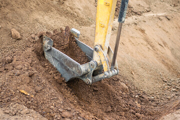 A mini excavator is digging the soil in the field.