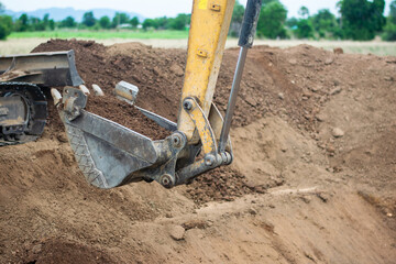 A mini excavator is digging the soil in the field.