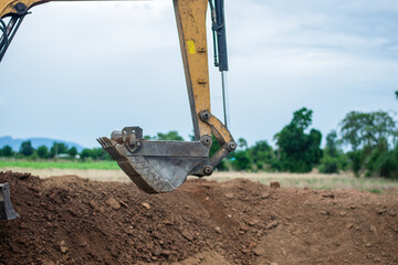 A mini excavator is digging the soil in the field.