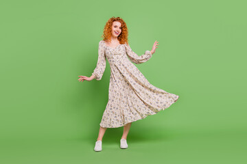 Full size photo of positive happy charming young woman fly dress skirt isolated on green color background