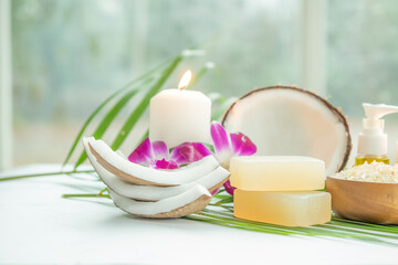 Fototapeta na wymiar Coconut oil, tropical leaves and fresh coconuts. Spa coconut products on light wooden background. Spa still life of organic cosmetics with coconuts on a light wooden background, body care concept.