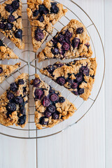 Freshly baked oat blueberry scones on cooling rack on white wooden background. Sweet food with natural ingredients. Vegan gluten free pastry..