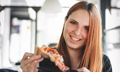 young teenager redhead girl eating pizza in cafe