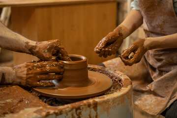 Hands of the skilled master Potter and woman hands, training of the woman to production of pottery on a Potter wheel