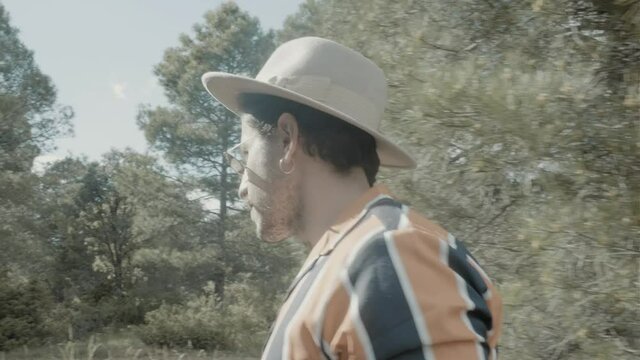 A man with a hat and a mustache lost in the woods.