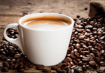 cup of coffee with coffee beans on wooden background